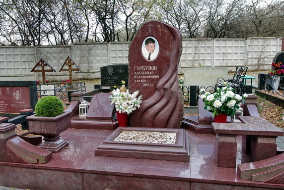 Вертикальная стела из чёрного гранита с резной юбкой и краем под естественный скол
